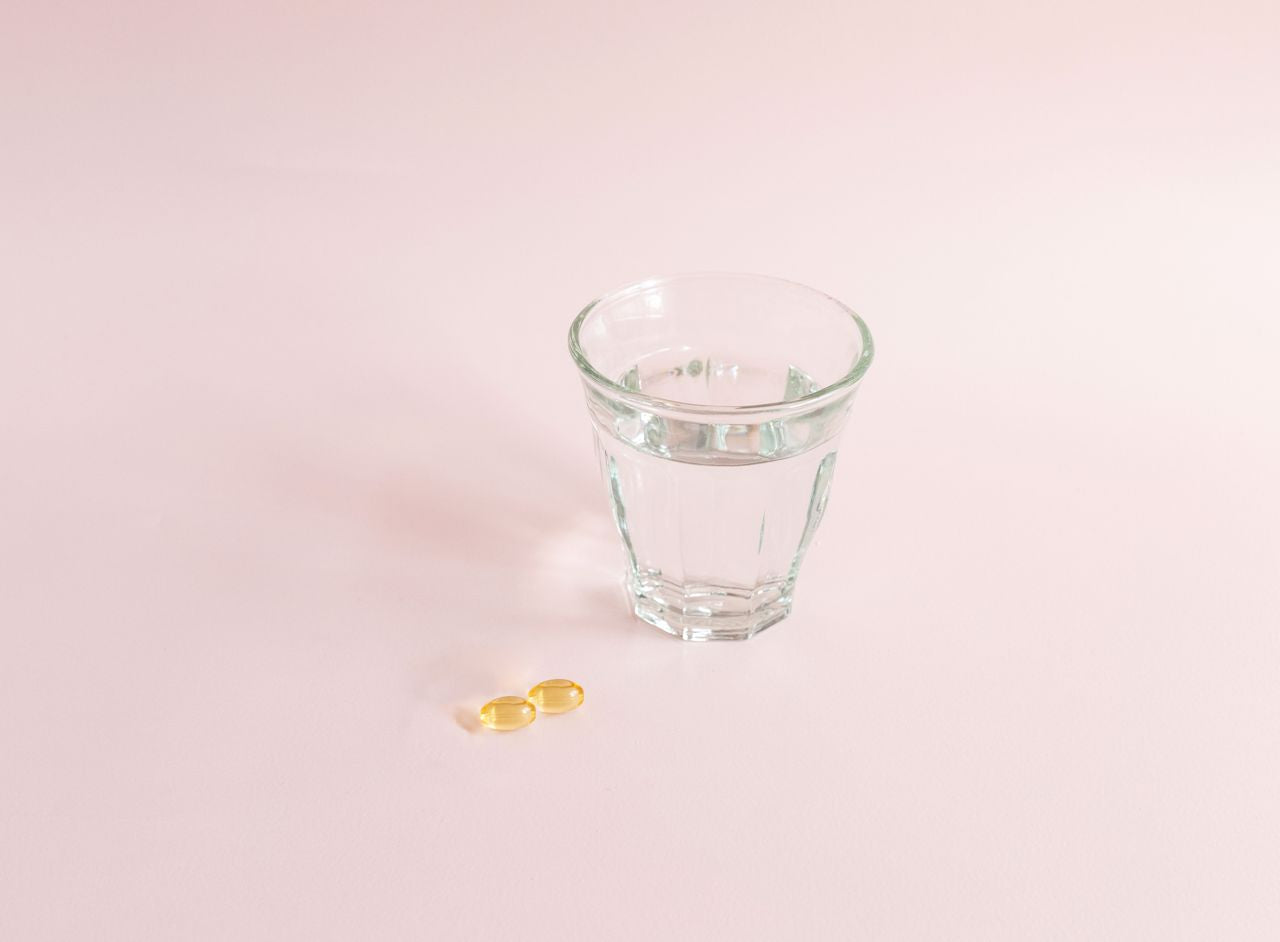 Sanaexpert Omega-3 due capsule con bicchiere di acqua