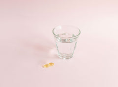 Sanaexpert Omega-3 due capsule con bicchiere di acqua