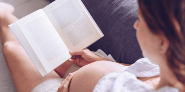 pregnant-woman-reading-book-on-the-sofa