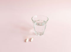 SanaExpert LeberVital Pro due capsule con bicchiere di acqua